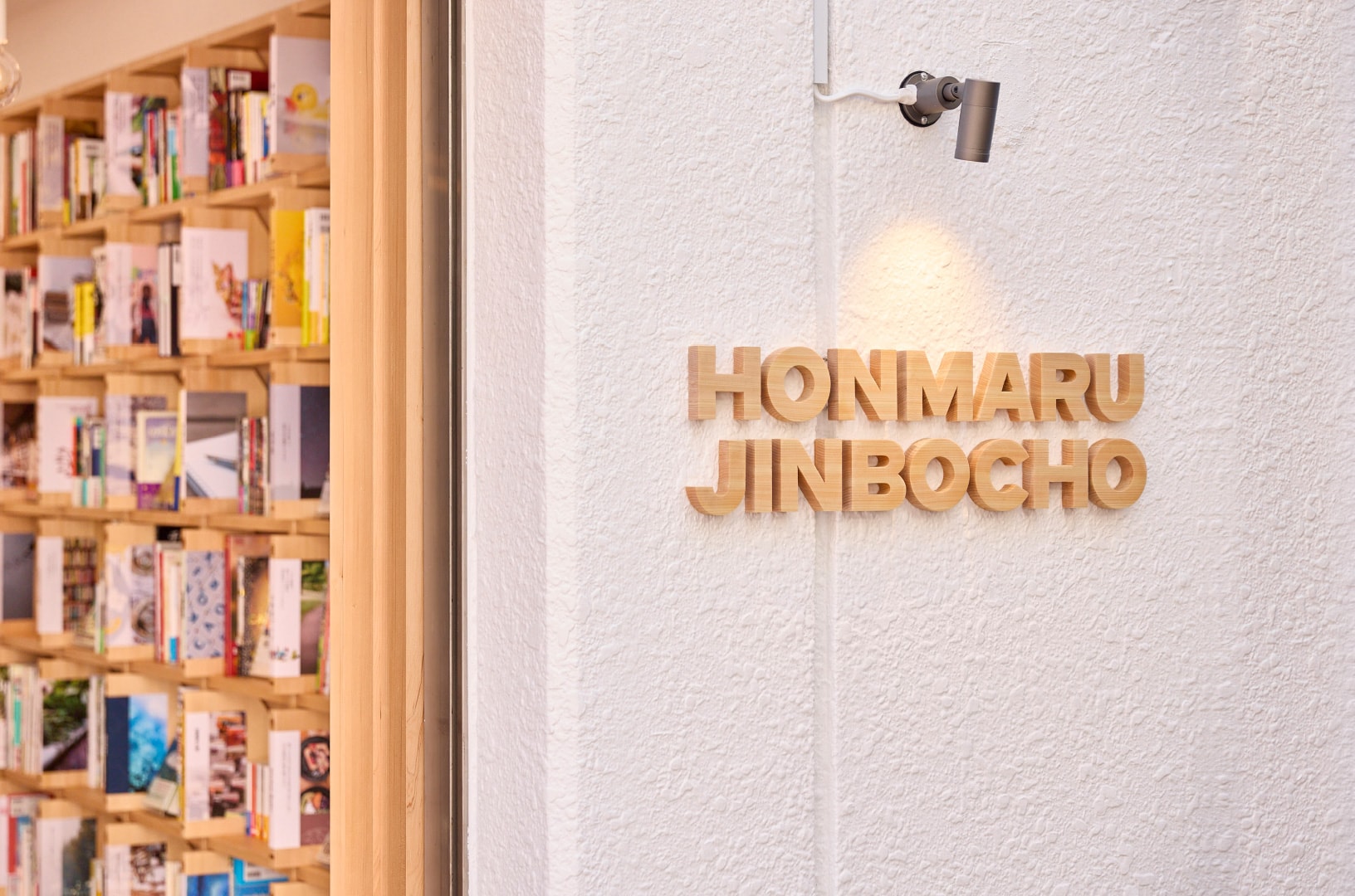 白い外壁と「HONMARU JINBOCHO」と書かれた木製のサイン